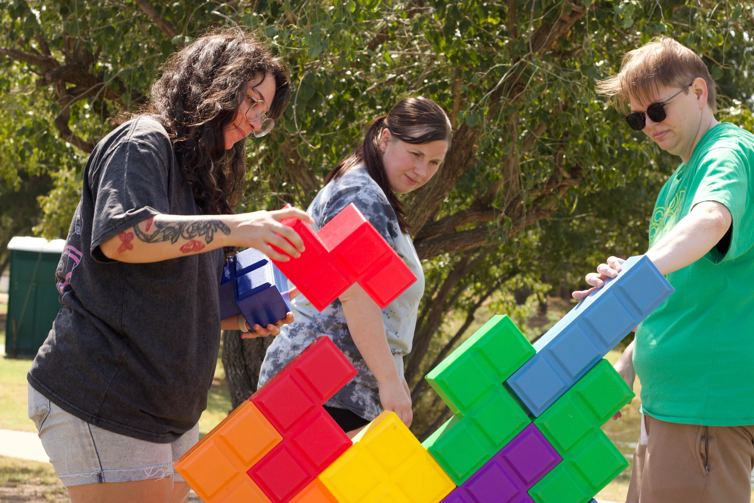 Three teammates steady their colorful Tetris tower.